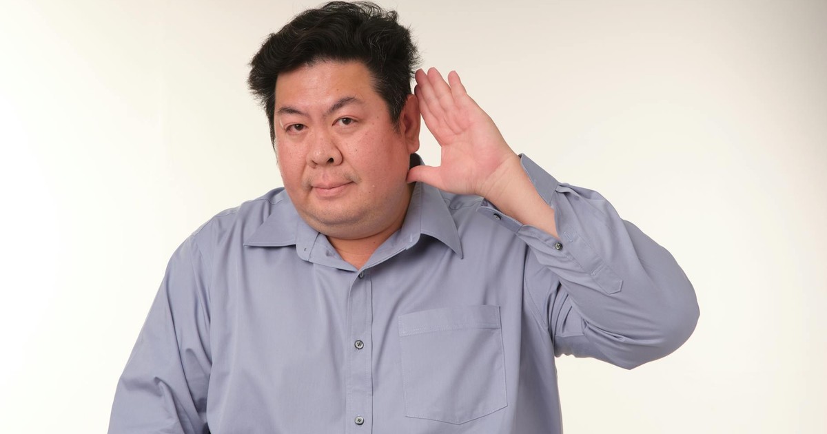 A man in a pose demonstrating the gesture of listening in a studio setting.