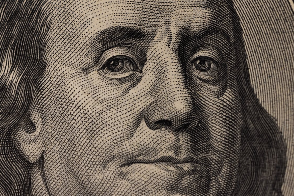 Detailed view of Benjamin Franklin's face on a US dollar bill, showcasing fine engraving