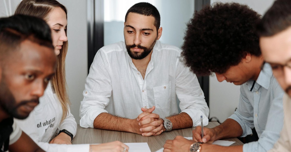 A diverse team of adults collaborating in an office meeting, showcasing teamwork and professionalism.