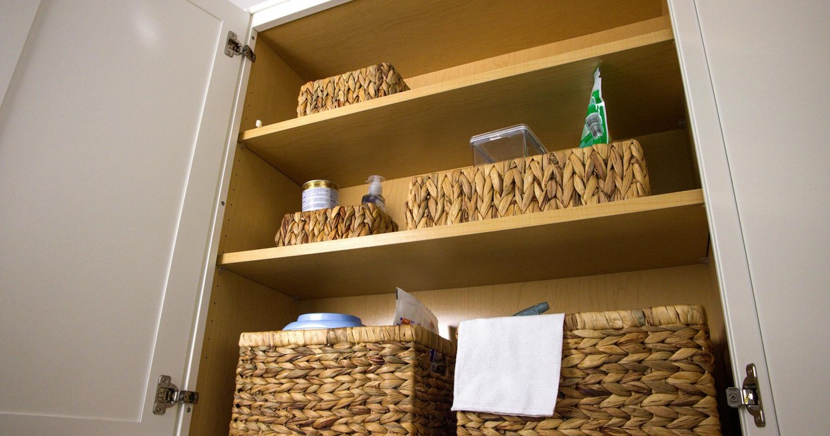 Neat storage in a kitchen cabinet using wicker baskets for a clean aesthetic and organization.