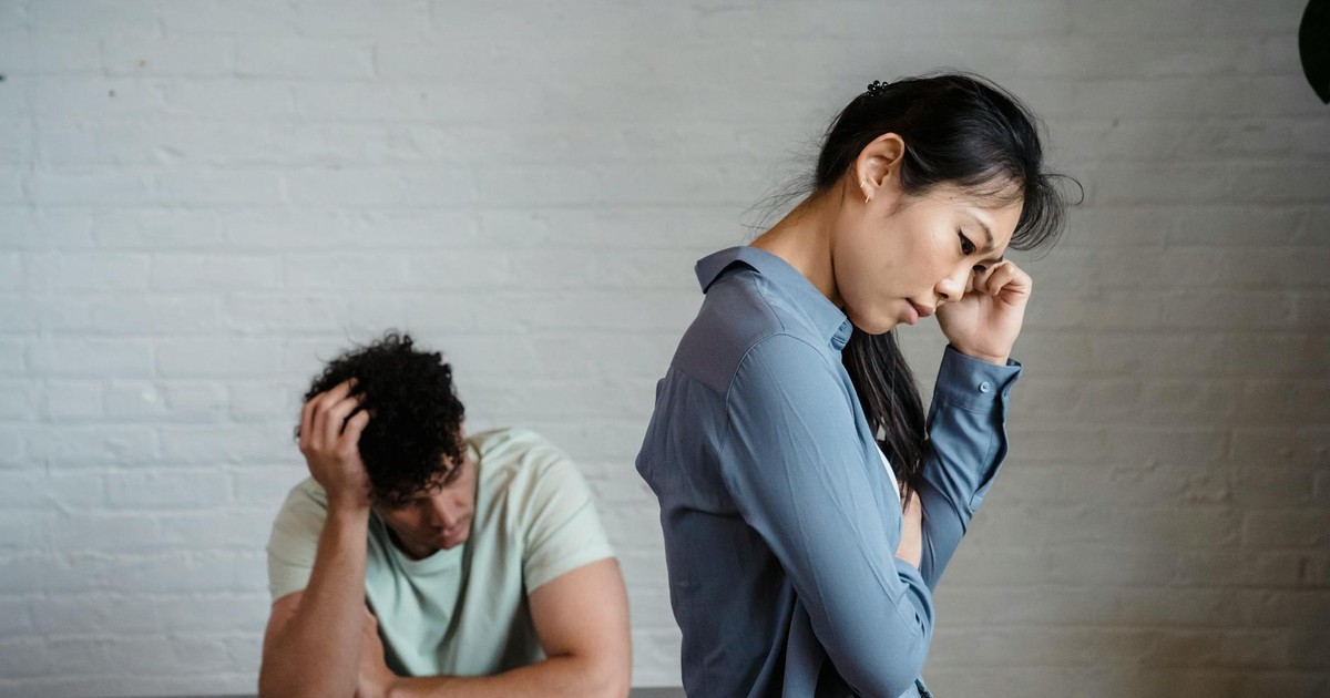 An Asian woman and man feeling misunderstood and frustrated in a relationship indoors.