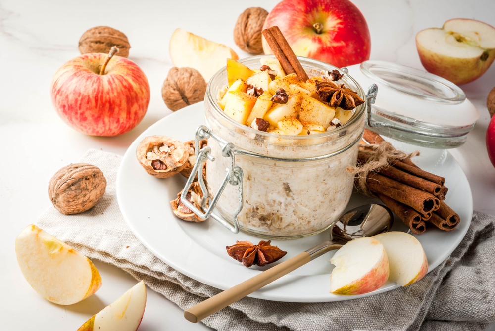Dietary breakfast or snack. Apple pie overnight oats, with apples, yogurt, cinnamon, spices, walnuts. In a glass, on a white marble table.