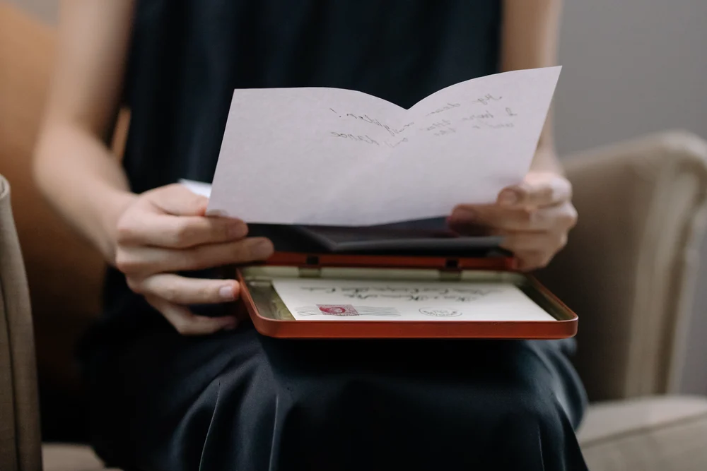 An adult woman holding and reading a handwritten letter in an intimate home setting