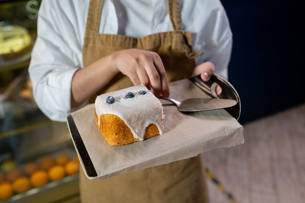 Close-up of a baker icing a delicious blueberry cake in a modern bakery setting