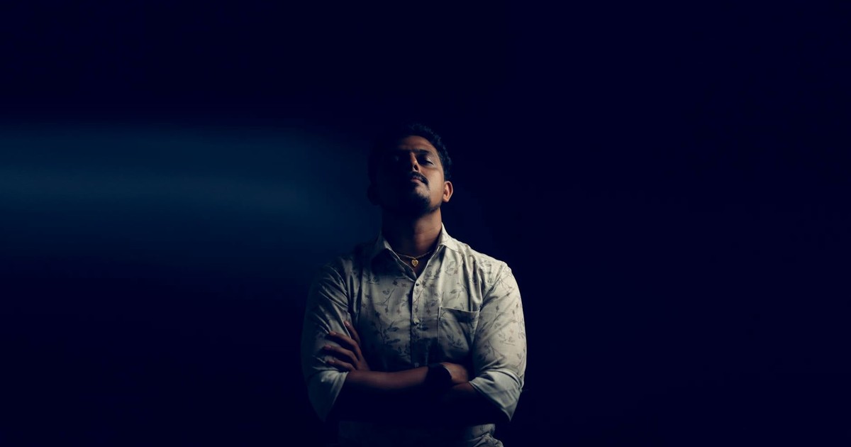Stylish portrait of a man posing elegantly against a dark backdrop in a studio setting, showcasing his confidence.