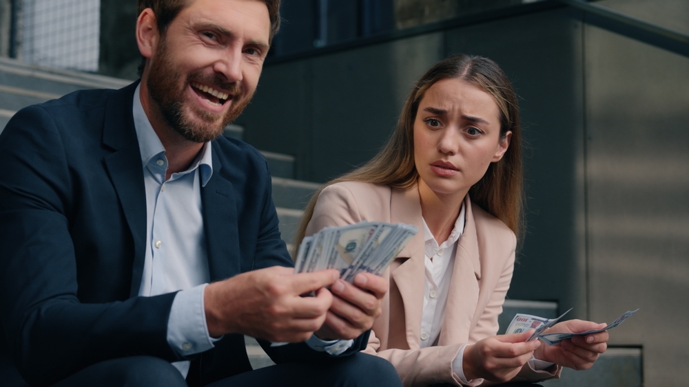 man and woman with money representing pay gap