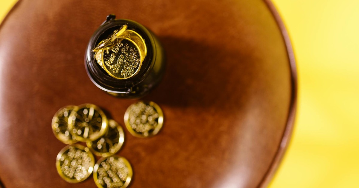 Overhead shot of gold coins on a brown surface against a yellow background.