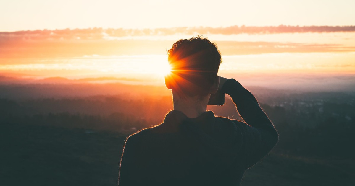 Silhouette of a man at sunrise, capturing the vibrant sky and serene landscape