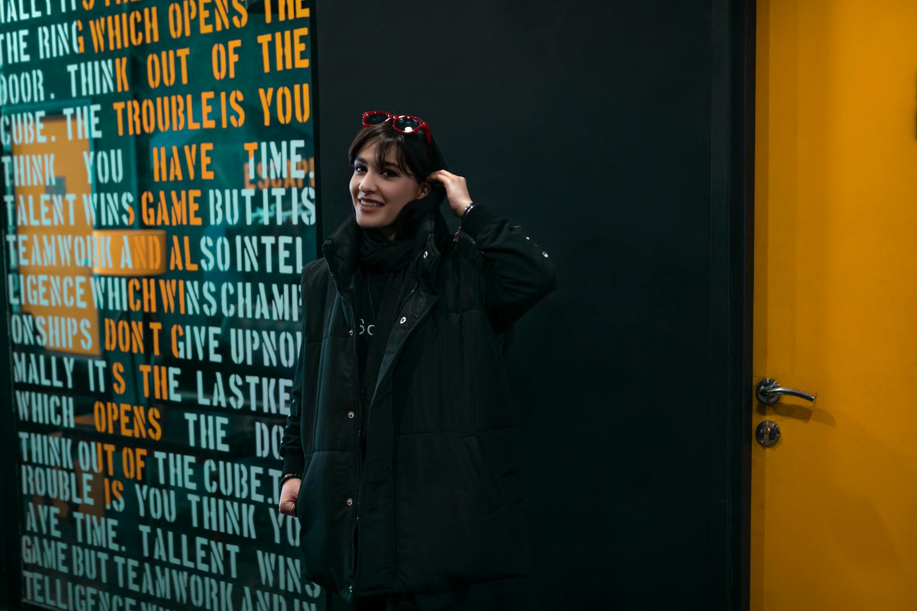 Smiling woman in sunglasses and black coat in front of motivational text in Tehran.