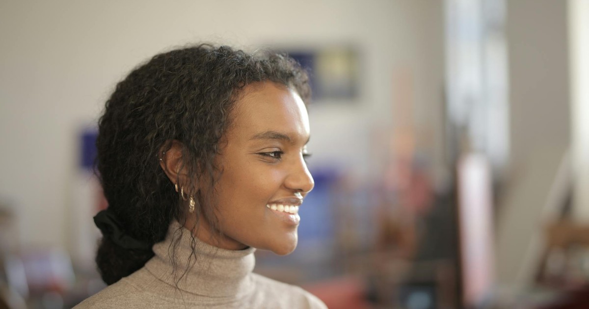 Profile of a smiling woman indoors, exuding warmth and positivity in natural light.