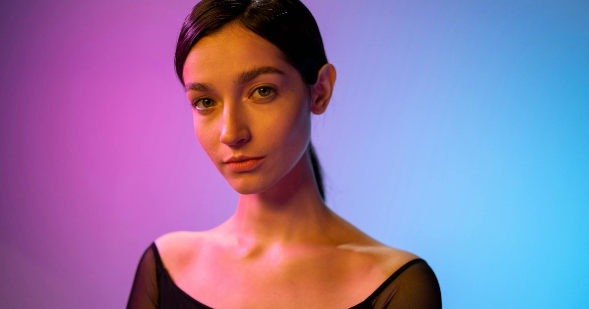 A striking portrait of a woman in a studio with creative colored lighting effects.