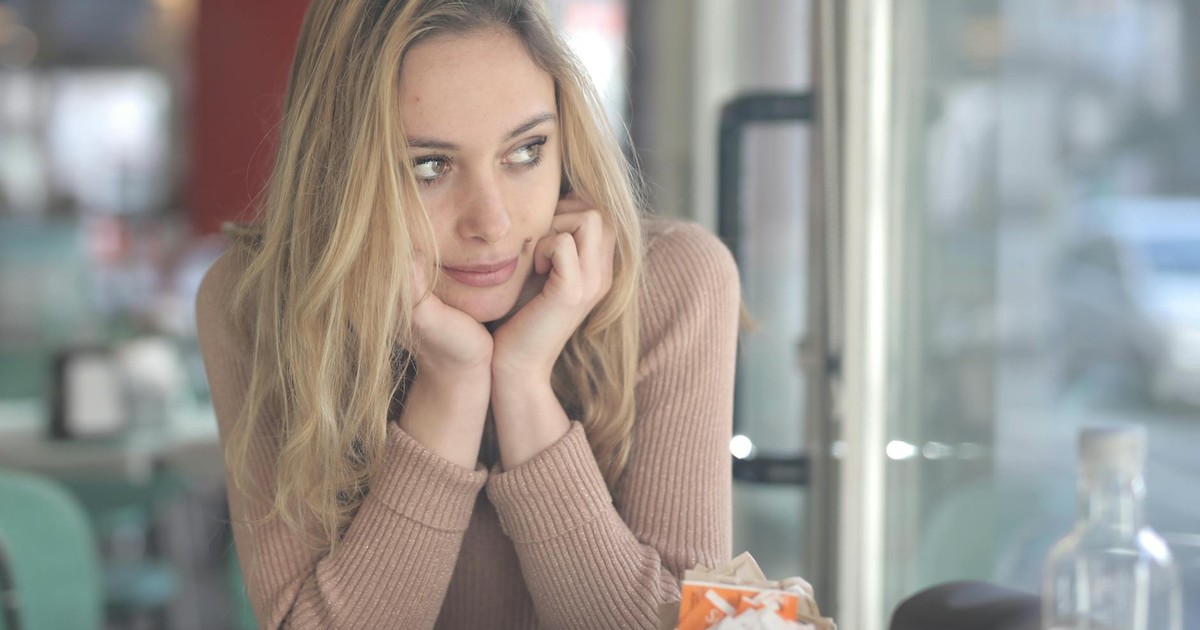 A woman in a cafe looking contemplative with a coffee cup nearby, captured with Canon EOS 5DS.