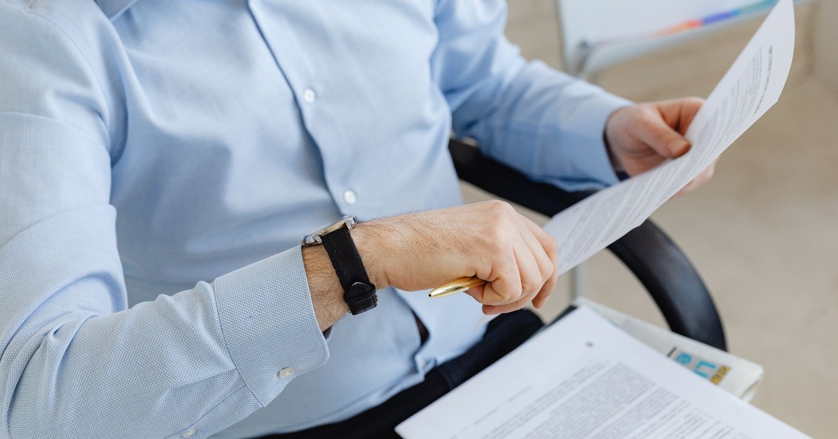 Businessman reviewing papers in office setting, highlighting analysis and attention to detail.