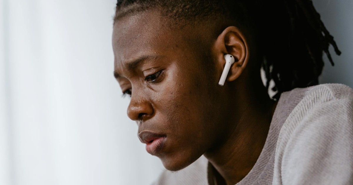 Side profile of a focused individual wearing wireless earphones, conveying introspection.