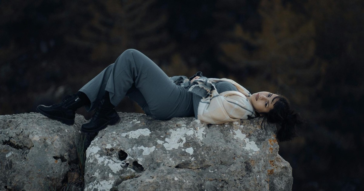 A serene moment of a woman lying on a large rock in nature, showcasing tranquility.