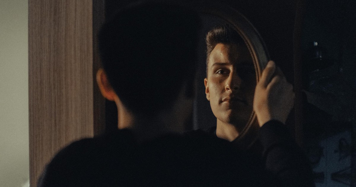 A man gazing at his reflection, capturing an introspective moment indoors.