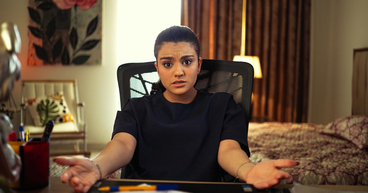 A woman looking confused while working from home at a desk in her bedroom.
