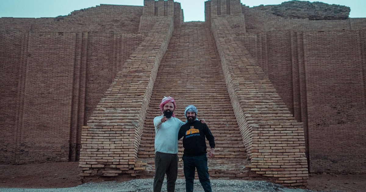 Two tourists pose at the ancient Ziggurat of Ur, a historical landmark in Iraq.