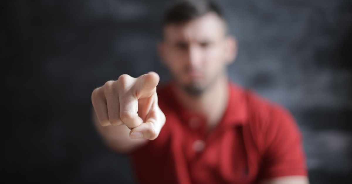 Blurred man pointing forward, emphasizing index finger close-up.
