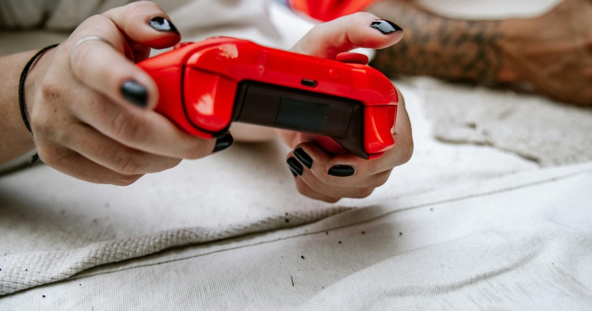 Close-up of hands holding a red game controller, perfect for gaming and technology themes.