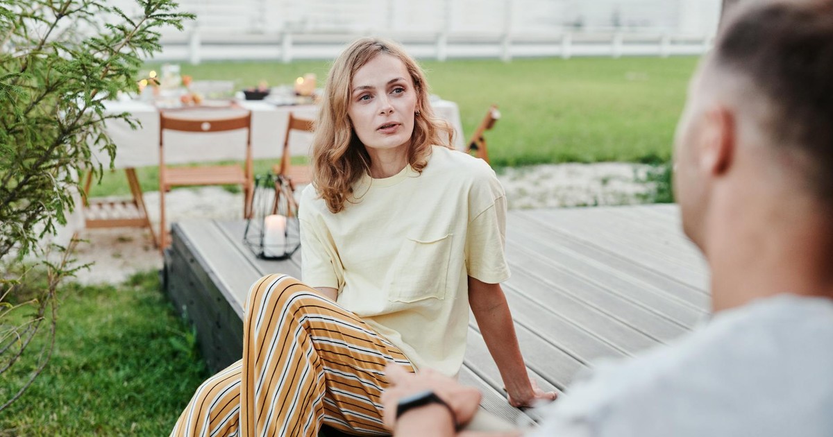 A couple engaged in a thoughtful conversation outdoors in a relaxed garden setting.
