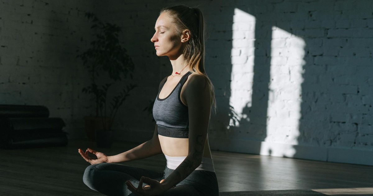 Woman in lotus position meditating indoors, embracing mindfulness and tranquility.