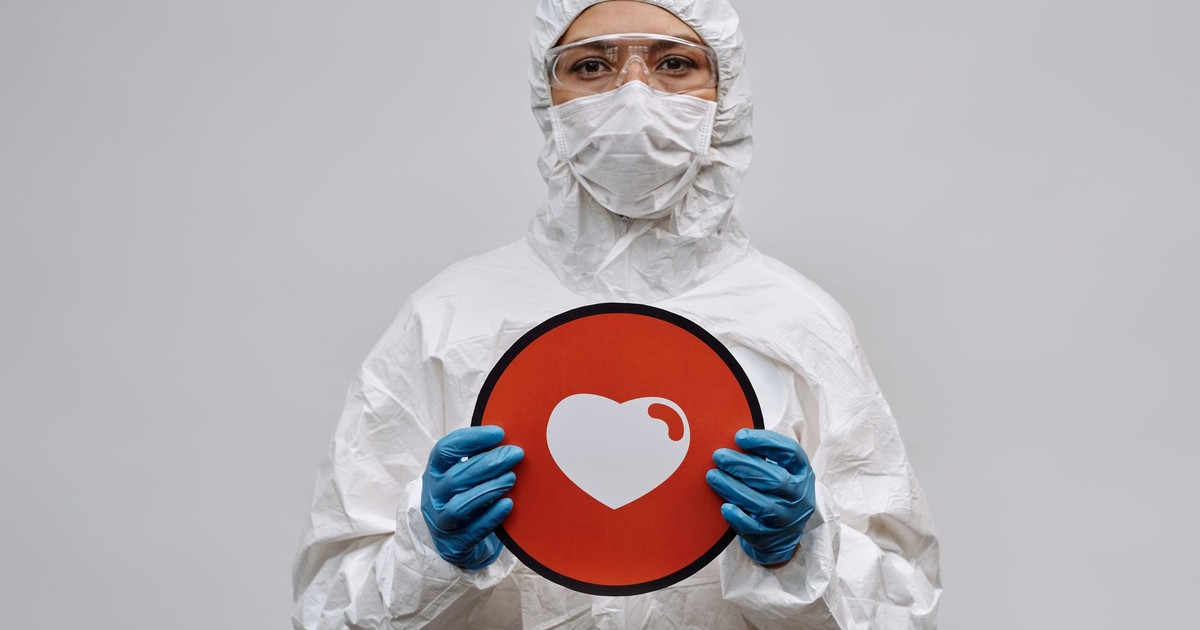 Individual in protective gear holding a heart symbol sign conveying care and protection.