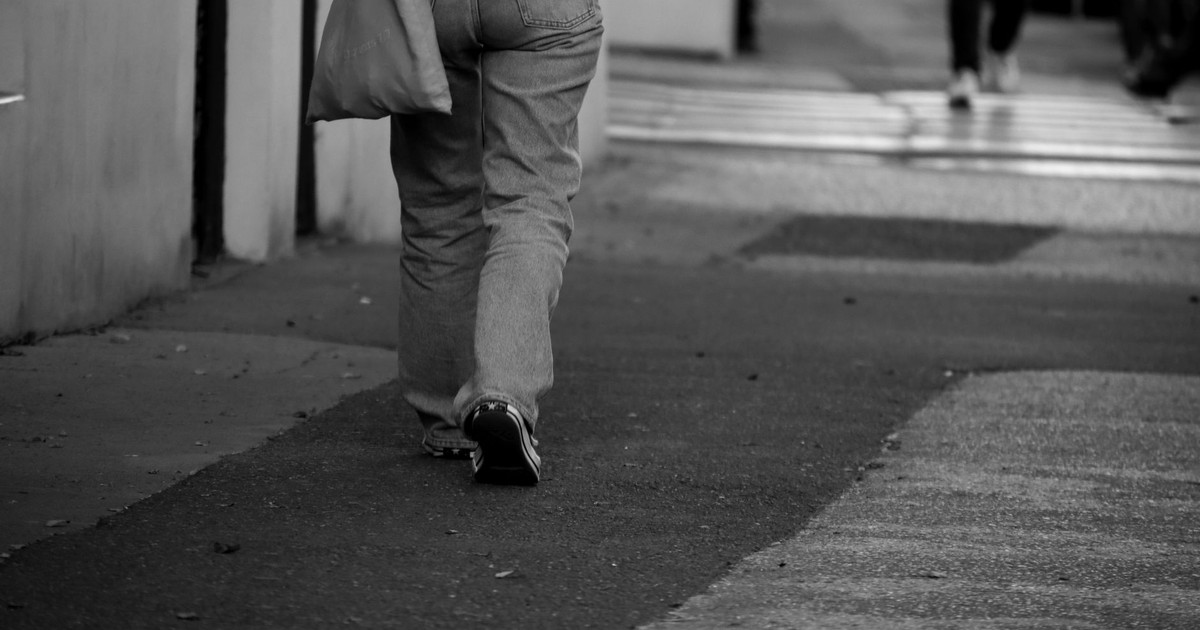 A monochrome photo of a person walking on a city sidewalk in Czechia.