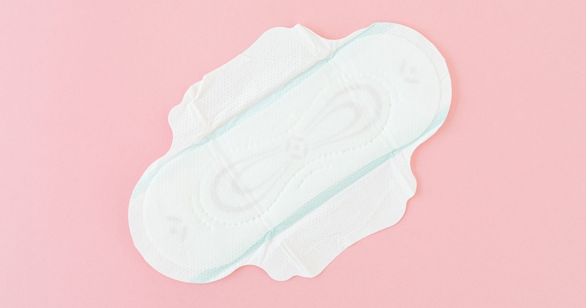 High-angle close-up of a sanitary pad on a pink background, emphasizing hygiene and care.