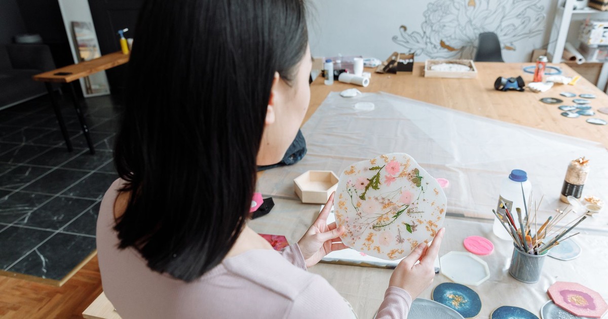 A woman artist crafting a decorative resin piece in a modern studio setting with various art materials.