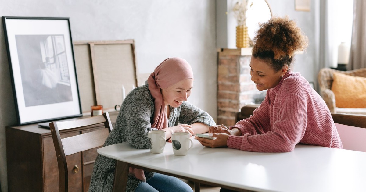 Two women enjoying a warm moment together indoors, sharing coffee and smiles.
