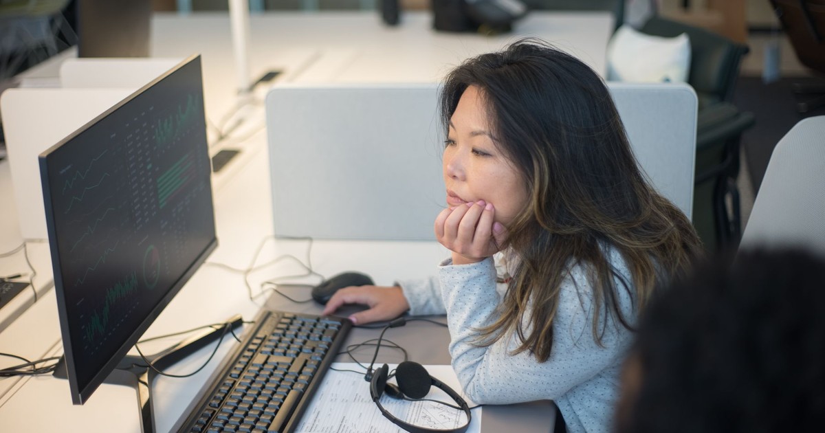 Woman intently viewing a computer monitor in a modern office environment.