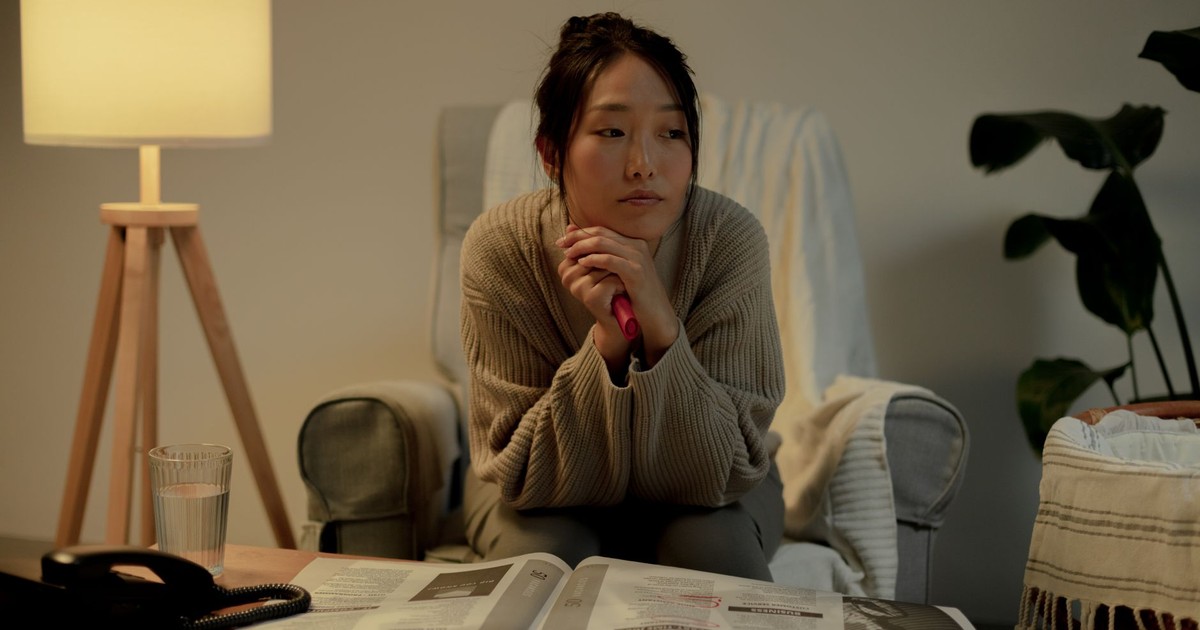A woman in an armchair, contemplating job search in a cozy living room.