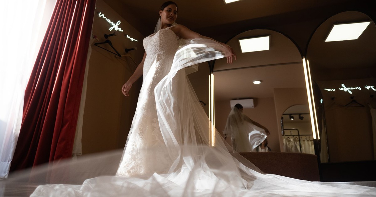 Bride in a wedding dress admiring her reflection in a chic dressing room, exuding elegance and anticipation.