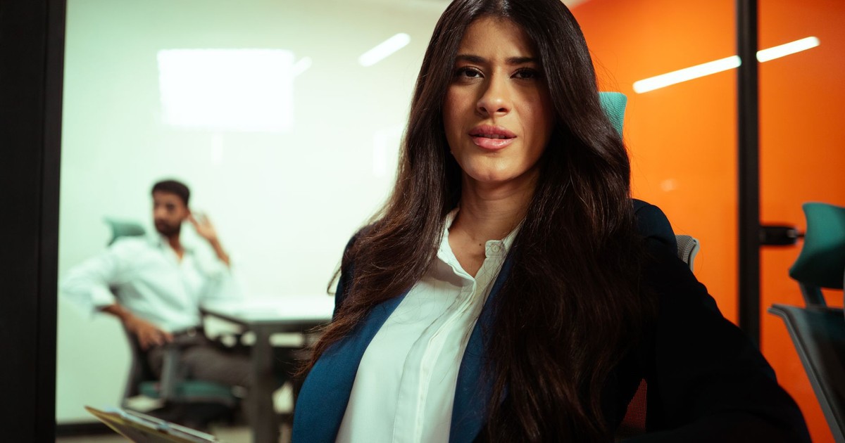 Confident young businesswoman with long hair in a stylish office. Professional and focused demeanor.