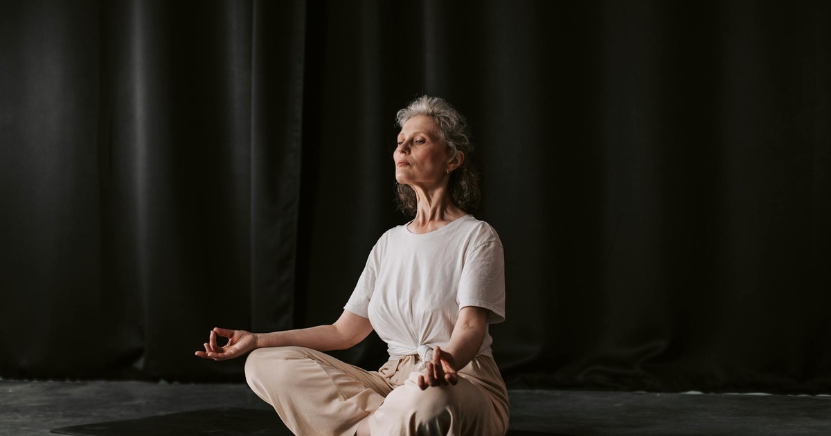 Senior woman practicing yoga in seated position indoors, focusing on mindfulness.
