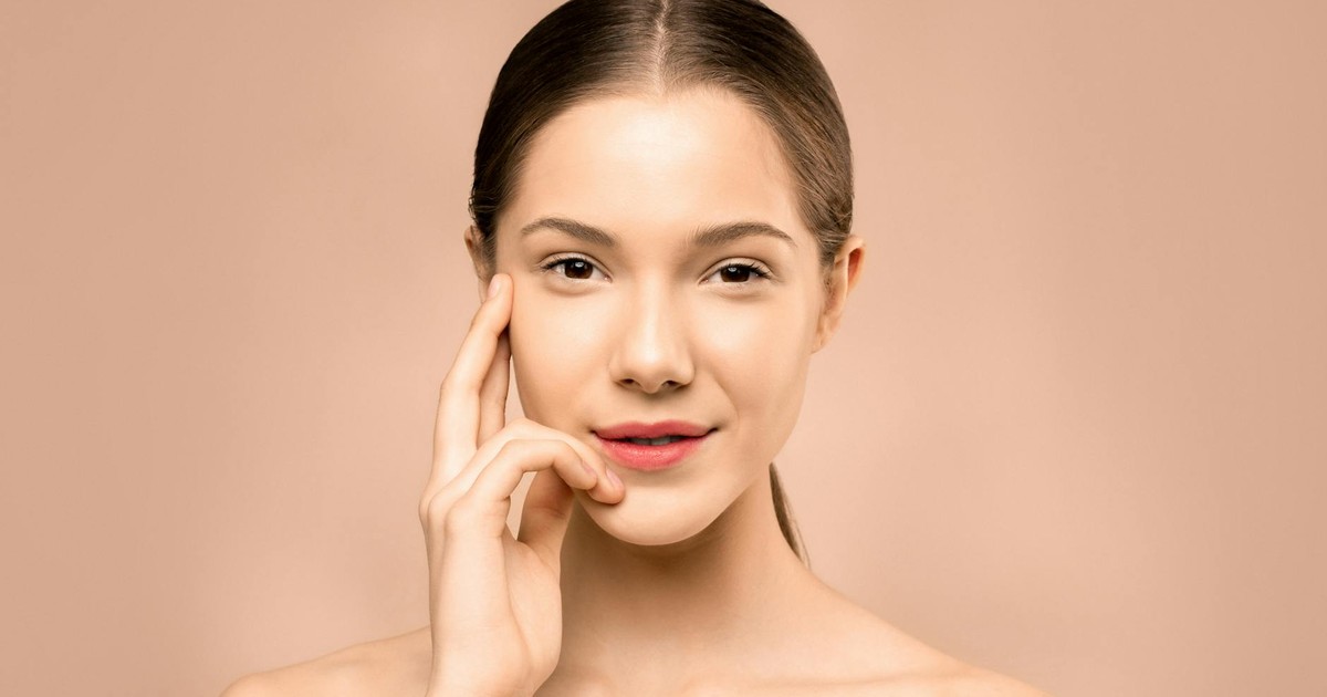 A close-up portrait of a young woman with flawless, radiant skin and a gentle smile, exuding natural beauty.