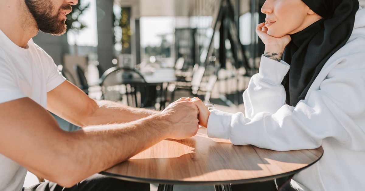 Couple holding hands and chatting at a cafe, showcasing cultural diversity