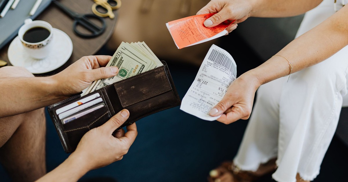 Close-up of a financial transaction involving cash and receipts over a coffee table.