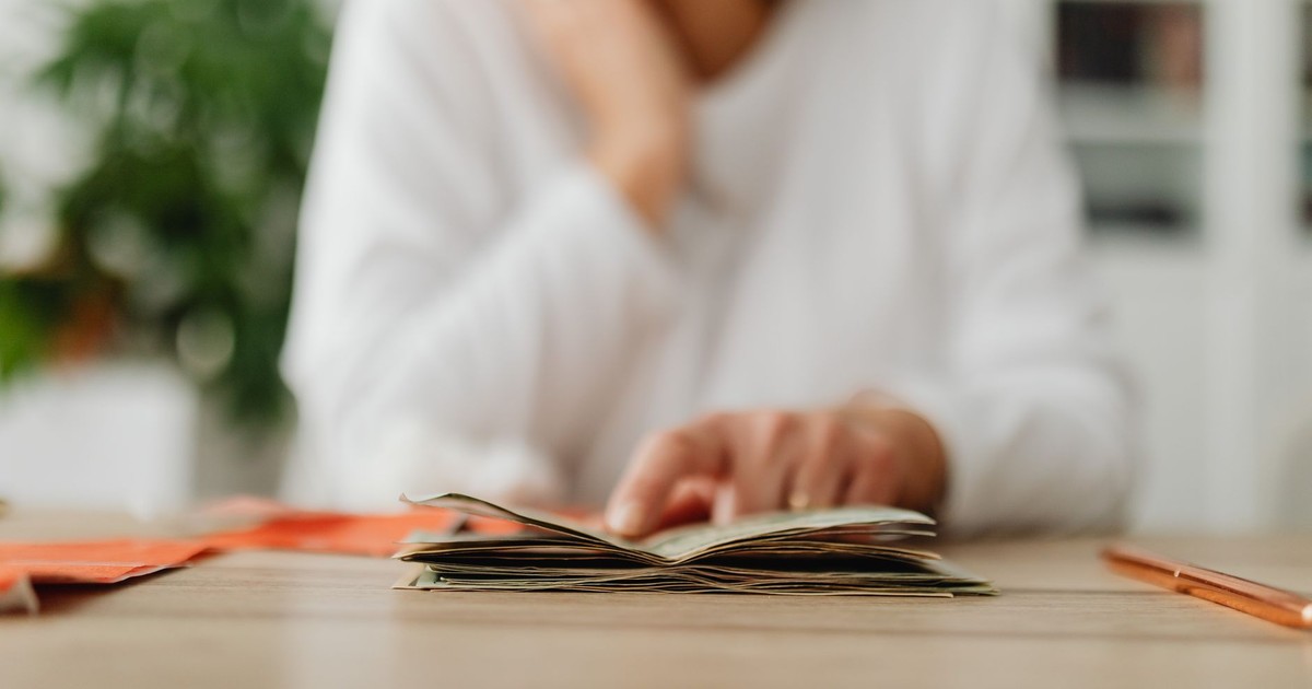 A woman sitting at a desk sorting through cash, focusing on household budgeting.