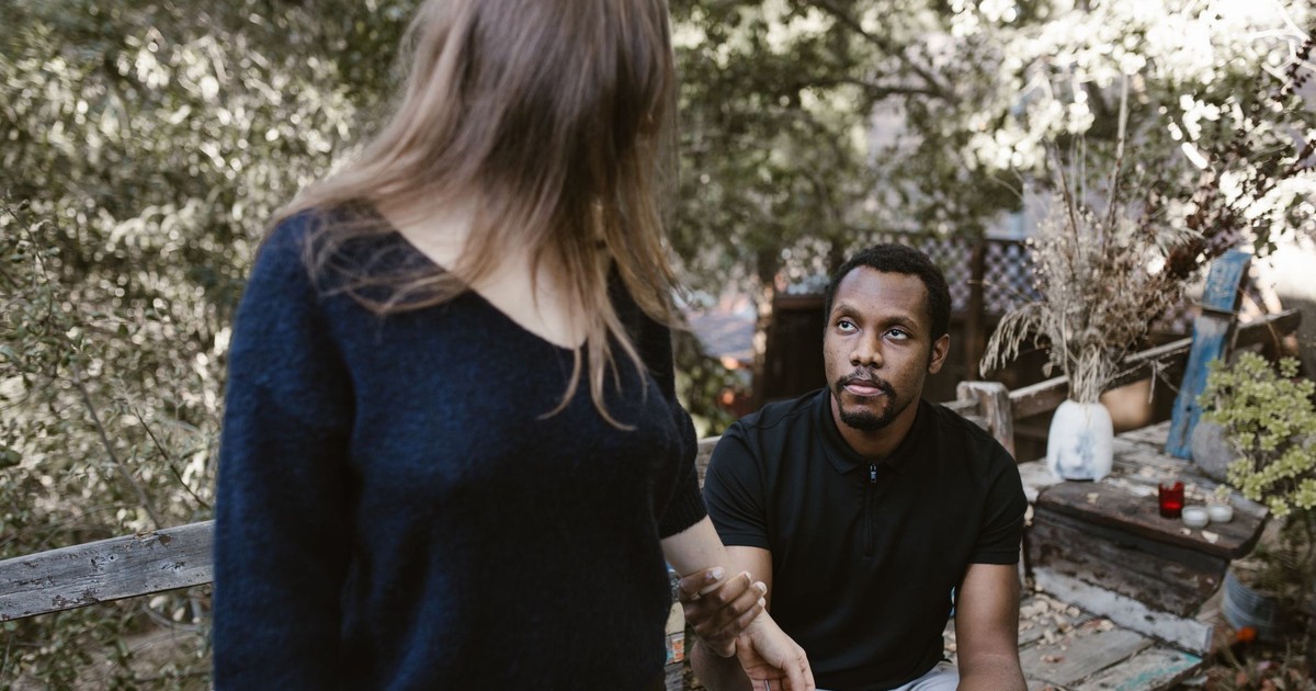 A couple in a serious discussion outdoors, surrounded by nature.