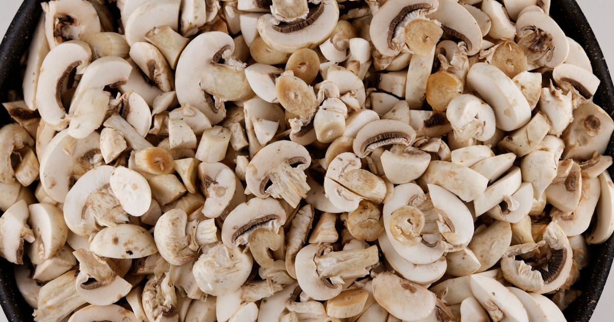 A close-up view of sliced mushrooms in a black bowl, showcasing their fresh texture and color.