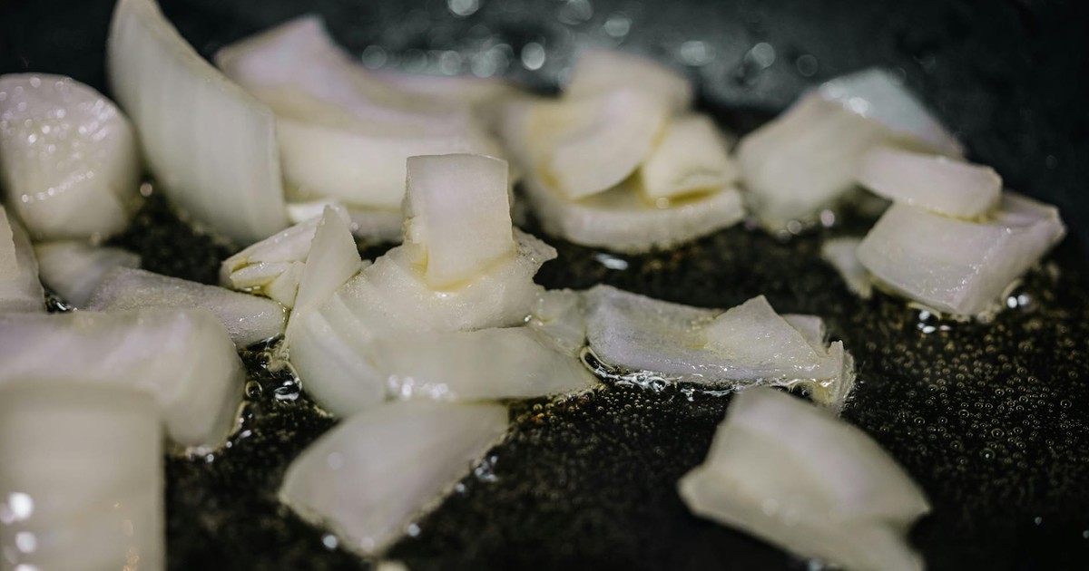 Close-up of chopped onions sizzling in oil in a frying pan, perfect for cooking blogs.