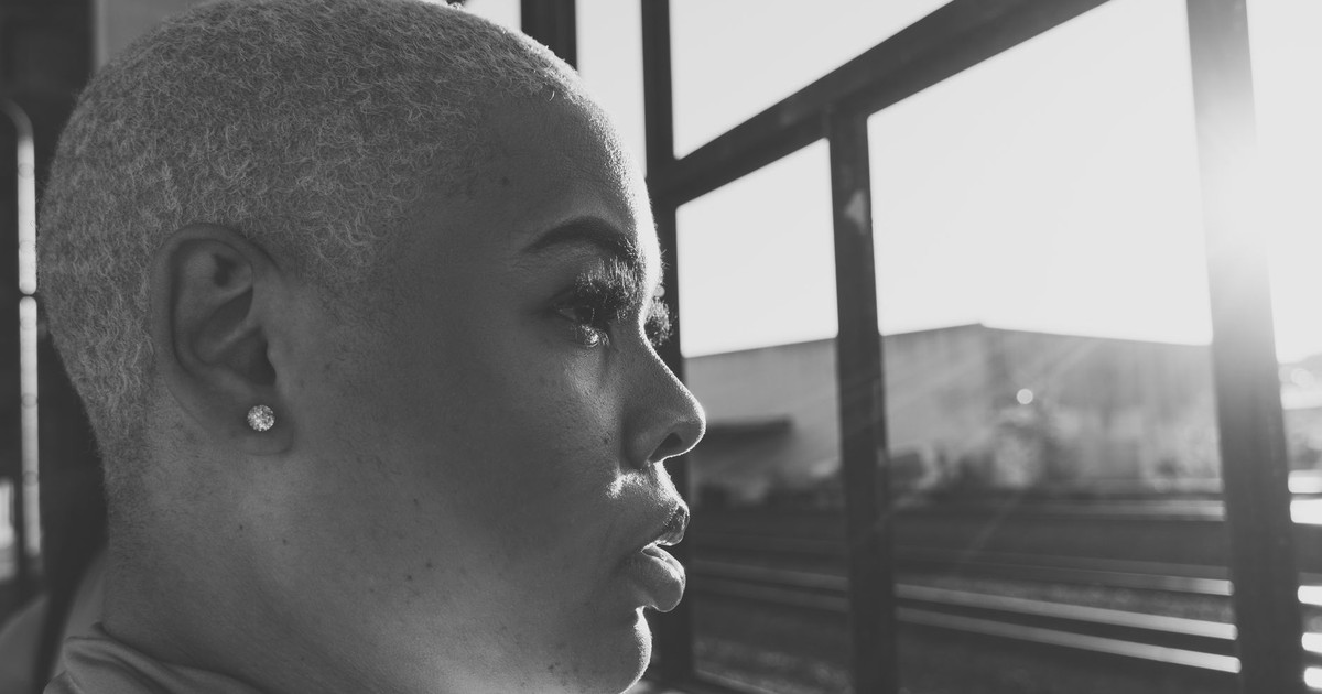 Black and white side profile of a woman with short hair and earring in sunlight.