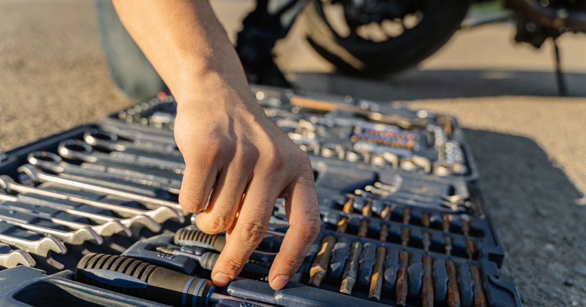 Close-up of a mechanic's hand selecting tools from a toolkit outdoors.