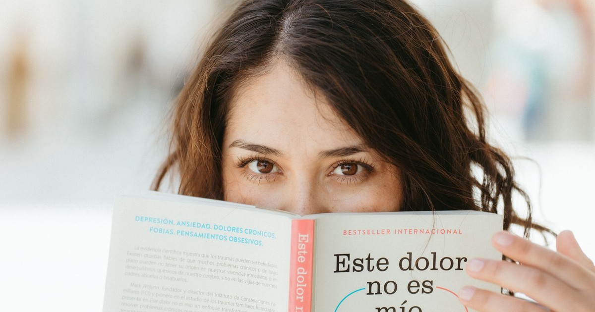 A woman reading a book titled 'Este dolor no es mío', focusing on mental health awareness.