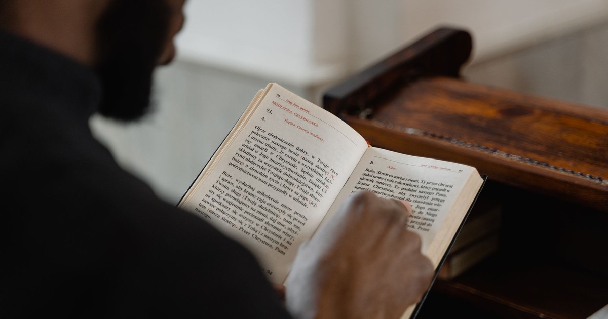 A man reading a religious book inside a church, focusing on a spiritual moment.