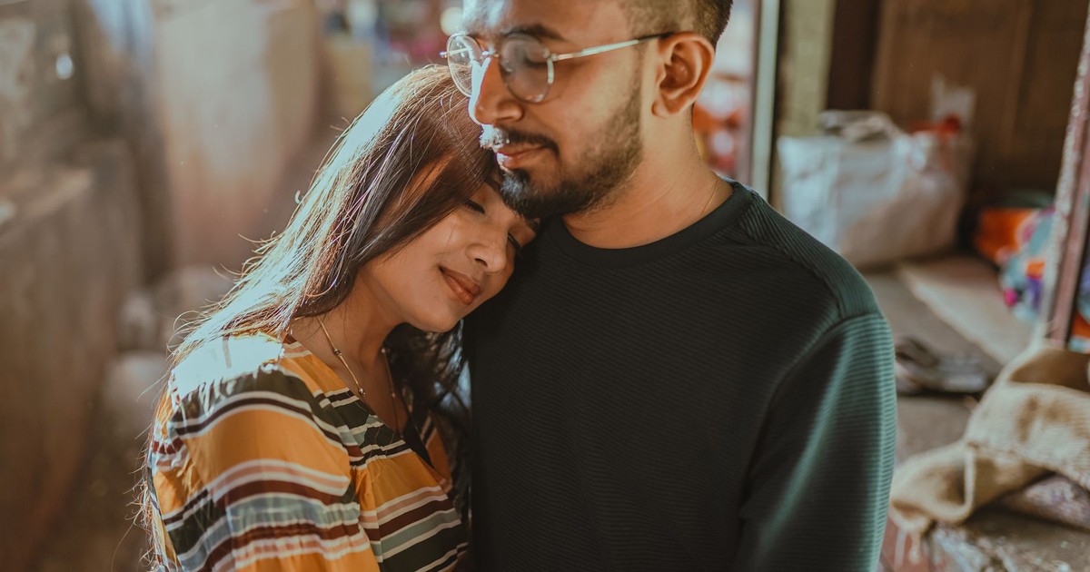 A loving couple enjoys a tender embrace in a cozy indoor setting, expressing warmth and closeness.