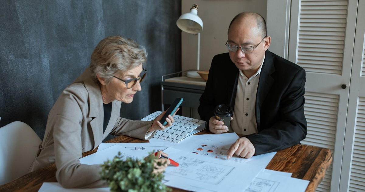 Diverse team of professionals working on project plans at a desk. Collaborative business environment.