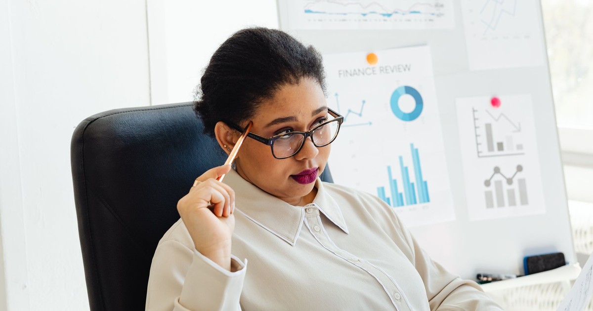 Focused woman reviewing financial graphs during a presentation in a modern office setting.